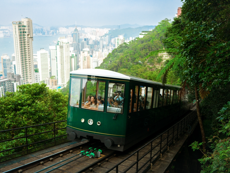 游客乘坐山顶缆车欣赏香港城市景色。