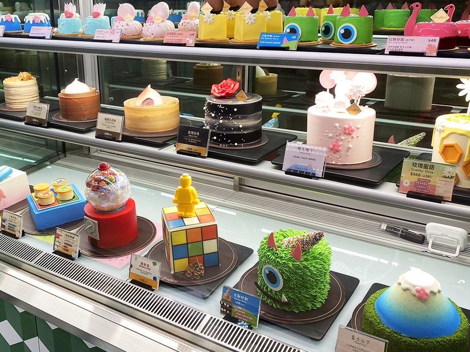 Twinkle Baker Décor的橱窗展示各式蛋糕，包括糖果机、魔方等造型。