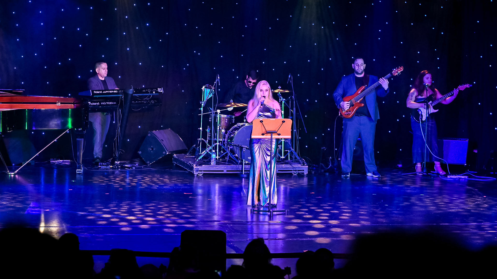 歌手在舞台上与现场乐队表演。