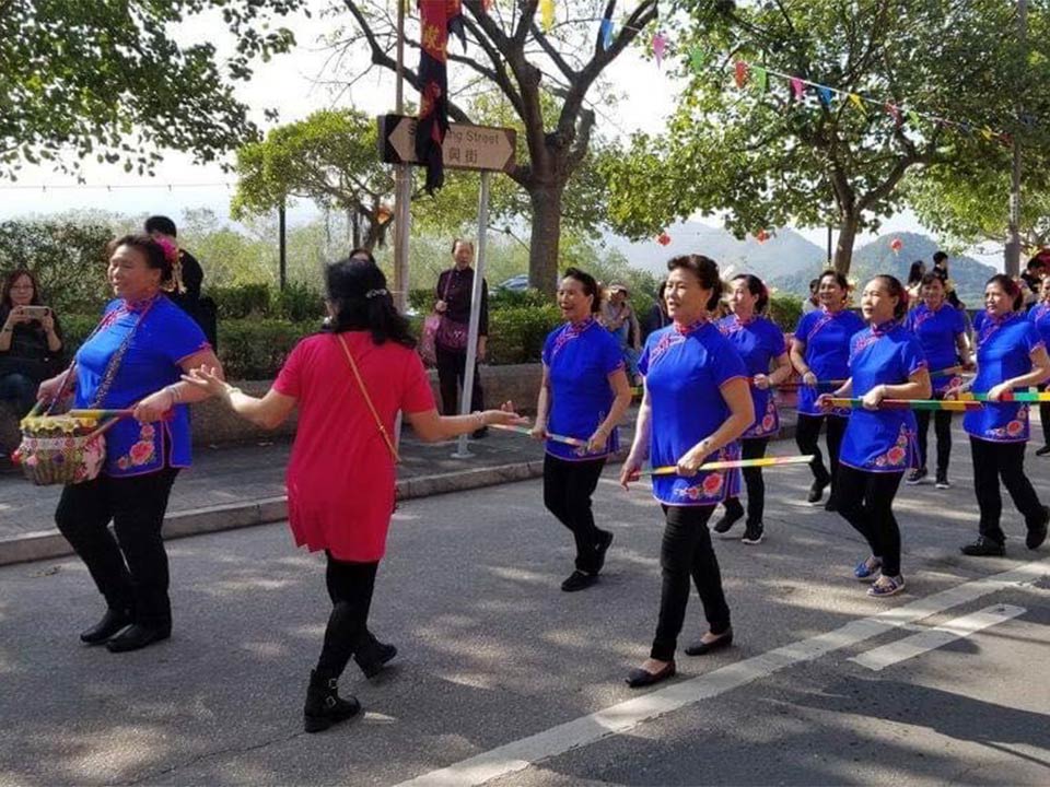 妇女一边唱小调一边手提船桨巡游